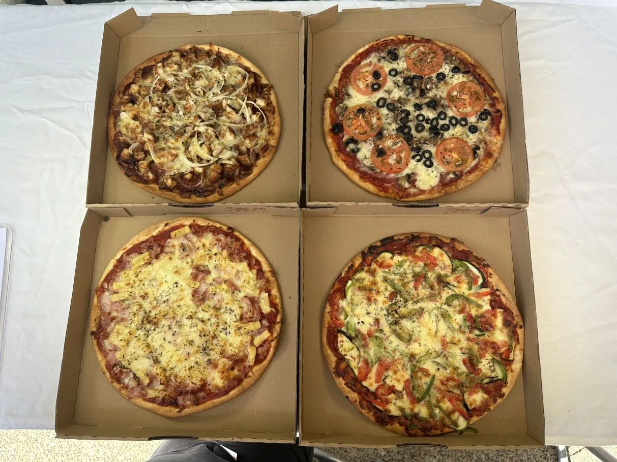 Four 12 inch pizzas in boxes ready for delivery across Cairns